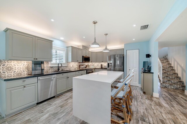 kitchen with sink, a center island, gray cabinets, pendant lighting, and stainless steel appliances