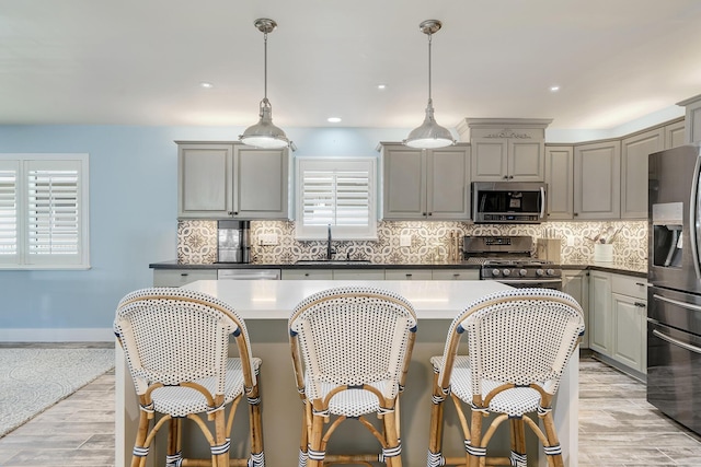 kitchen featuring sink, tasteful backsplash, hanging light fixtures, appliances with stainless steel finishes, and gray cabinets