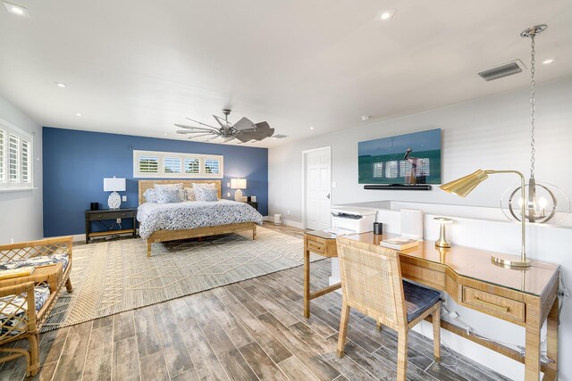 bedroom featuring hardwood / wood-style flooring, ceiling fan with notable chandelier, and multiple windows