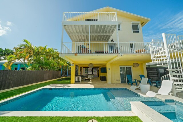 back of property featuring a swimming pool with hot tub, a balcony, and a patio area