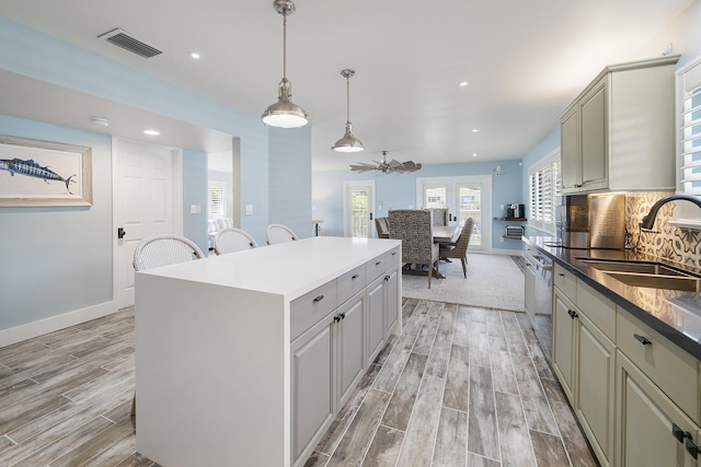 kitchen with pendant lighting, sink, decorative backsplash, a center island, and ceiling fan