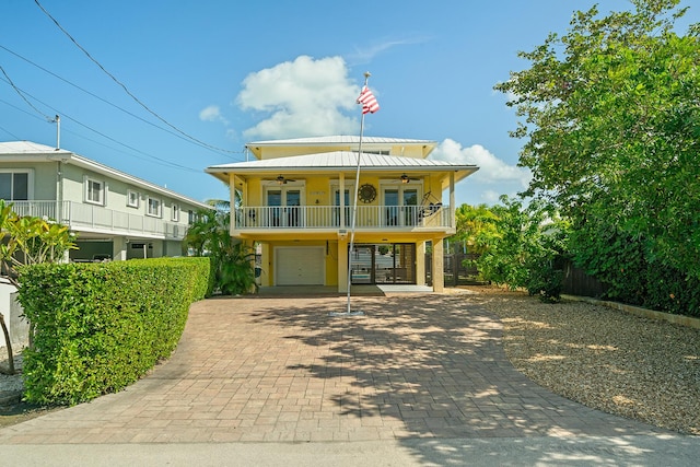 coastal home with a garage, a balcony, and ceiling fan