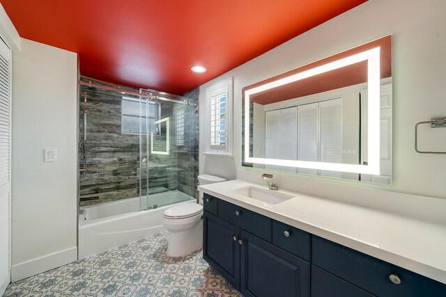 full bathroom featuring vanity, toilet, tile patterned flooring, and combined bath / shower with glass door