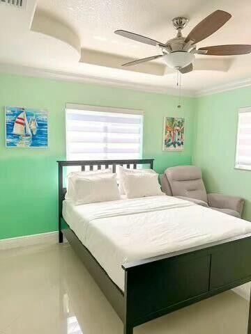bedroom featuring baseboards, multiple windows, ornamental molding, and a ceiling fan
