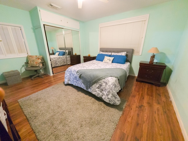 bedroom with visible vents, ceiling fan, baseboards, wood finished floors, and a closet