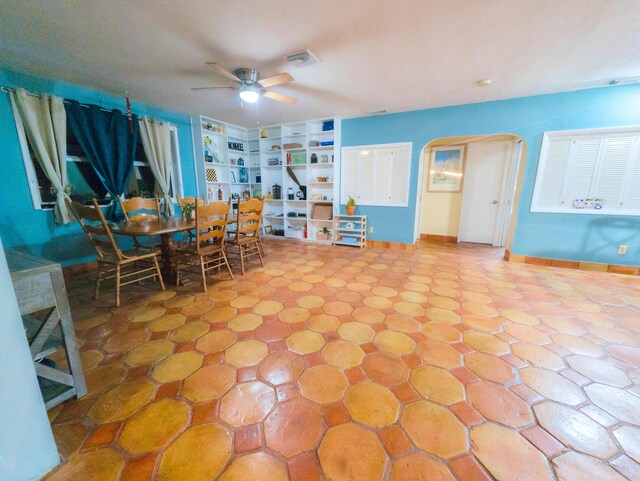 dining space with visible vents, ceiling fan, baseboards, built in features, and arched walkways