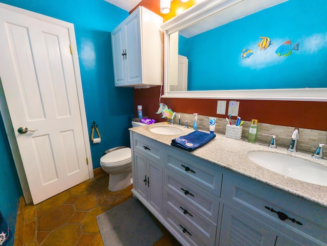 bathroom featuring double vanity, toilet, and a sink