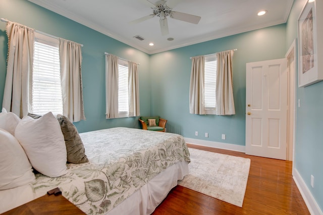 bedroom with multiple windows, hardwood / wood-style floors, and crown molding