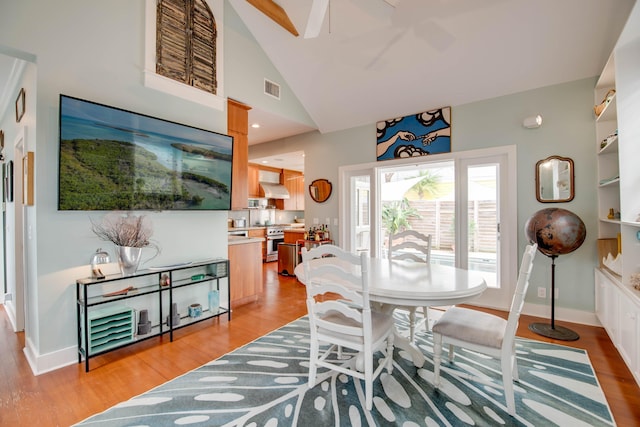 dining room with high vaulted ceiling and light wood-type flooring