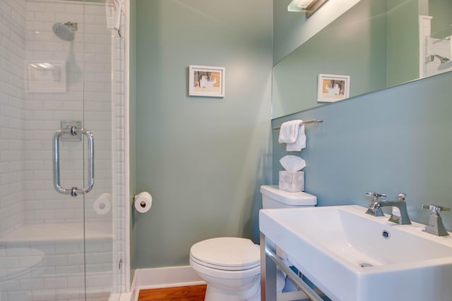 bathroom featuring sink, wood-type flooring, a shower with shower door, and toilet