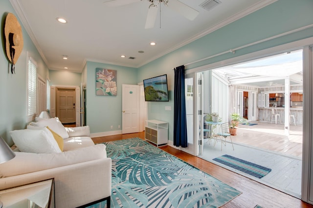 living room featuring hardwood / wood-style flooring, ornamental molding, and ceiling fan