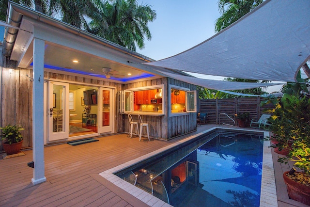 view of swimming pool featuring an outdoor bar, ceiling fan, and a deck