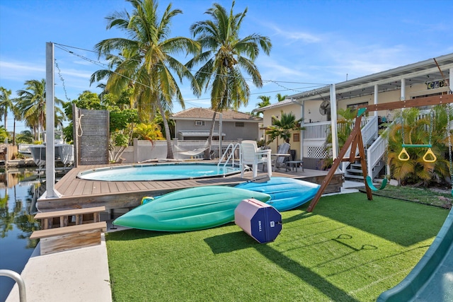 view of swimming pool with a water view, a lawn, and a boat dock