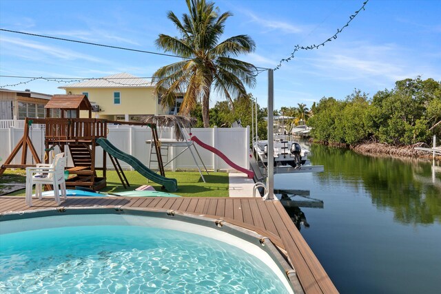 view of pool featuring a playground, a water view, and a dock