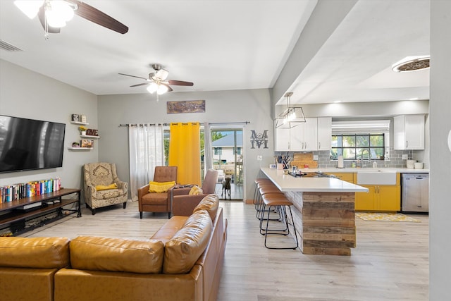 living room featuring sink, ceiling fan, and light wood-type flooring