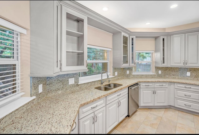 kitchen featuring dishwasher, white cabinetry, sink, decorative backsplash, and light stone countertops