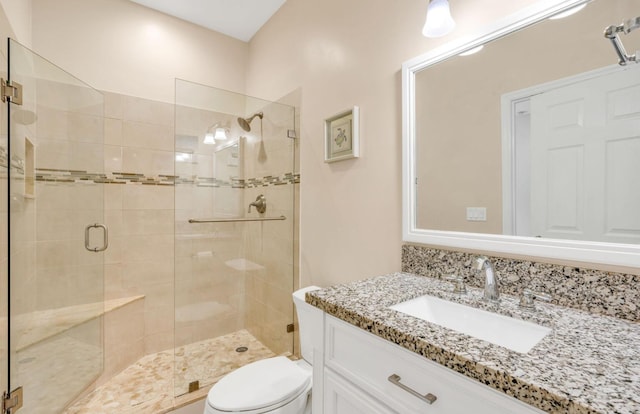 bathroom featuring vanity, a shower with shower door, and toilet