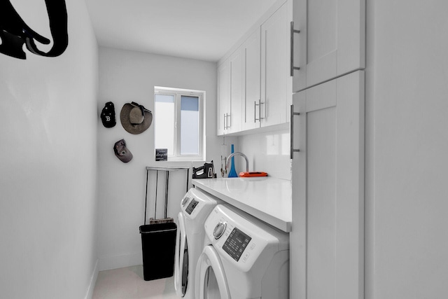 clothes washing area with cabinets and washing machine and clothes dryer