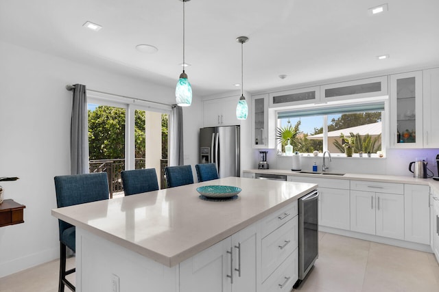 kitchen with white cabinetry, a kitchen island, stainless steel fridge, and a breakfast bar area