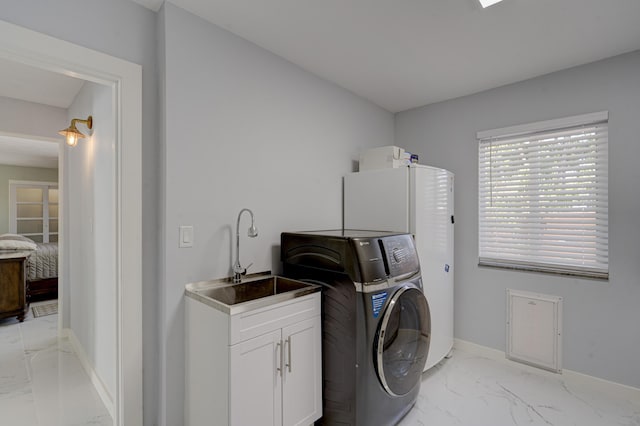 clothes washing area with cabinets, washer / clothes dryer, and sink