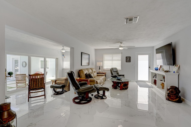 living room featuring ceiling fan and a textured ceiling