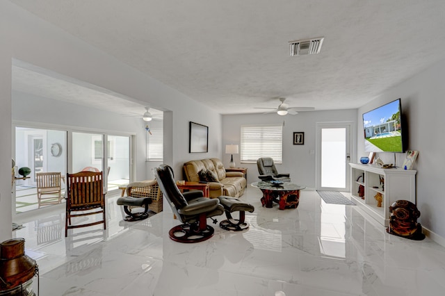 living room with ceiling fan and a textured ceiling