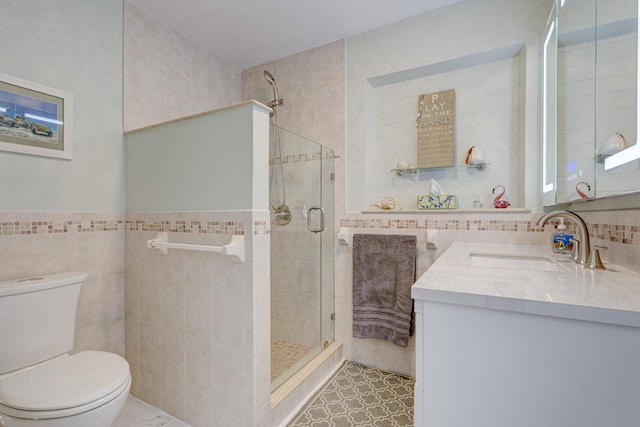 bathroom with walk in shower, vanity, toilet, and tile walls