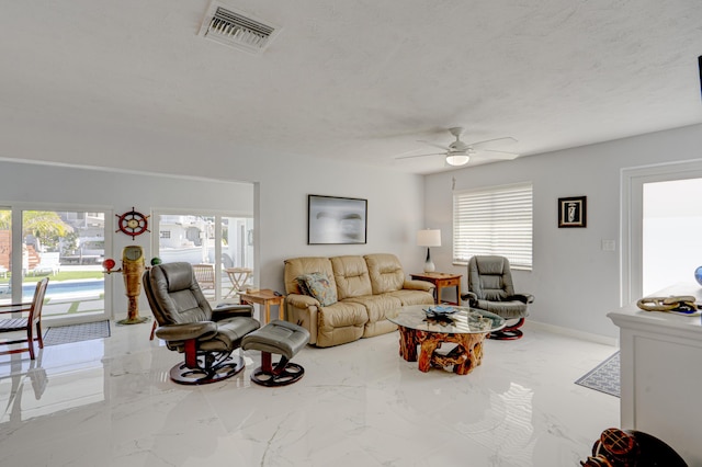 living room with ceiling fan and a textured ceiling