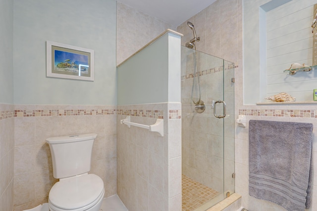 bathroom with tile walls, a shower with door, and toilet