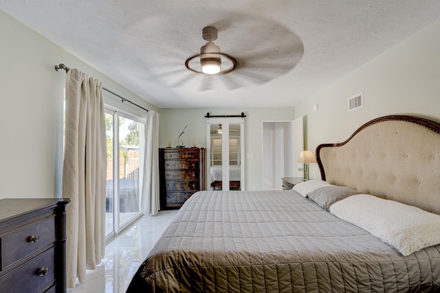 bedroom featuring ceiling fan, access to outside, a barn door, and a textured ceiling