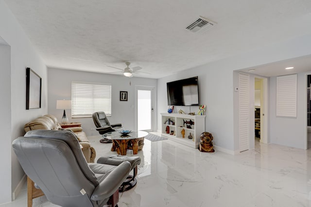 living room with ceiling fan and a textured ceiling