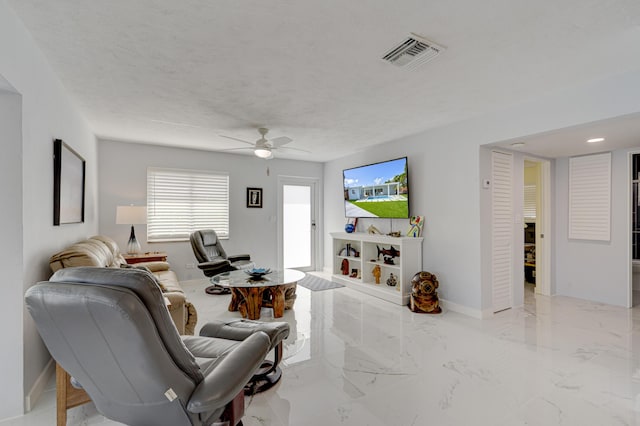 living room featuring ceiling fan and a textured ceiling