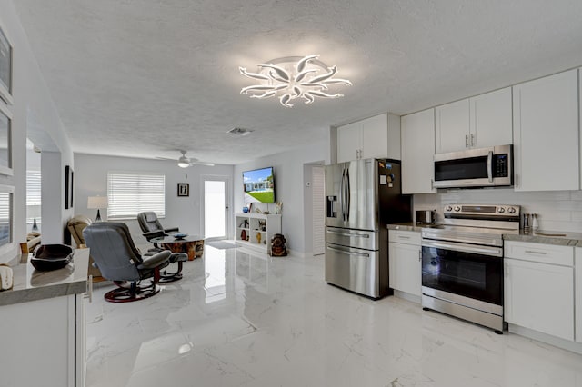 kitchen with appliances with stainless steel finishes, ceiling fan with notable chandelier, a textured ceiling, and white cabinets