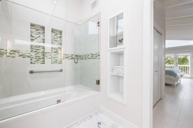 bathroom featuring bath / shower combo with glass door and built in shelves