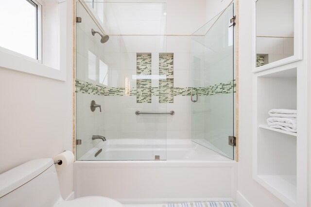 bathroom featuring shower / bath combination with glass door and toilet