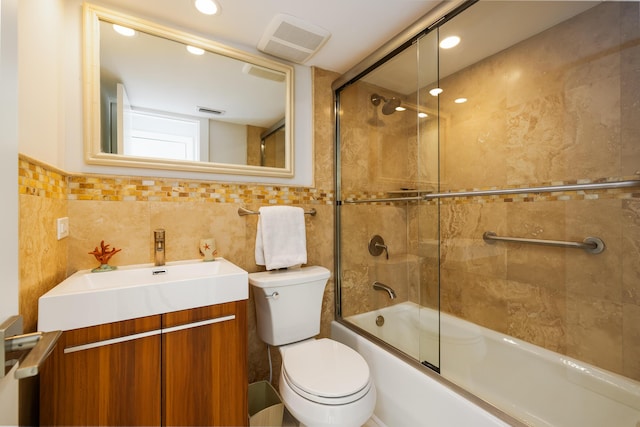 full bathroom with enclosed tub / shower combo, vanity, toilet, and tile walls