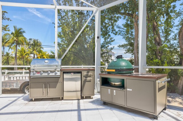 view of patio / terrace featuring area for grilling, a grill, and glass enclosure