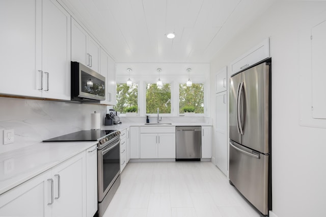 kitchen featuring sink, appliances with stainless steel finishes, white cabinetry, tasteful backsplash, and decorative light fixtures