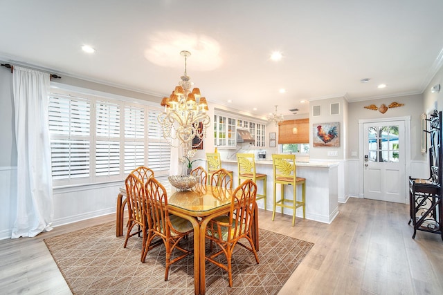 dining area featuring crown molding, light wood-type flooring, and a notable chandelier