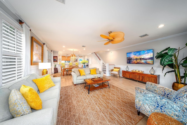 living room featuring ceiling fan, ornamental molding, and light wood-type flooring