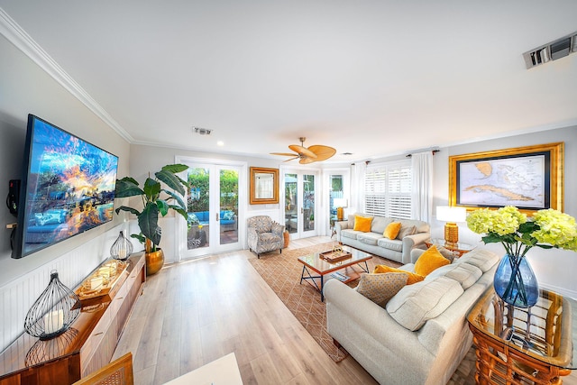 living room with ornamental molding, a wealth of natural light, light wood-type flooring, and french doors