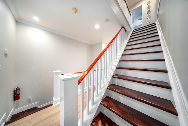 staircase featuring crown molding and wood-type flooring