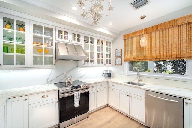 kitchen featuring appliances with stainless steel finishes, ventilation hood, sink, white cabinets, and hanging light fixtures