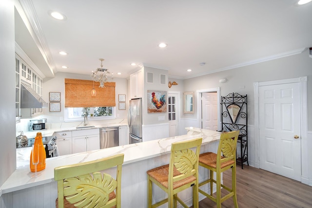 kitchen featuring a kitchen breakfast bar, kitchen peninsula, white cabinets, and appliances with stainless steel finishes