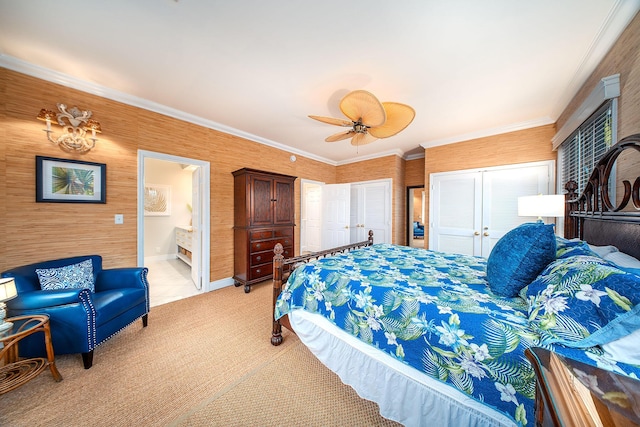 carpeted bedroom featuring ceiling fan, crown molding, ensuite bath, and multiple closets