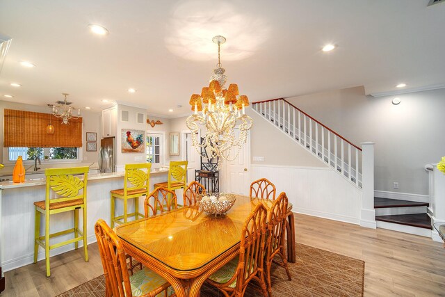 dining space featuring an inviting chandelier, ornamental molding, and light hardwood / wood-style floors