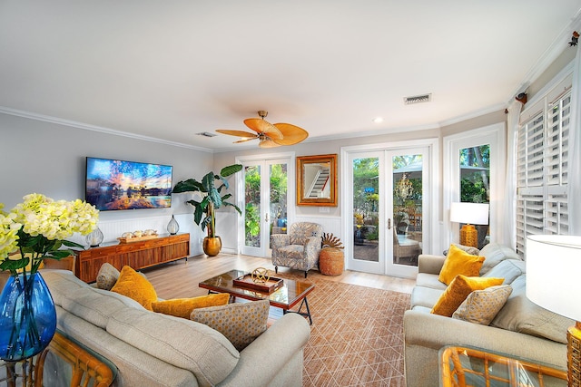 living room with ornamental molding, light hardwood / wood-style flooring, ceiling fan, and french doors