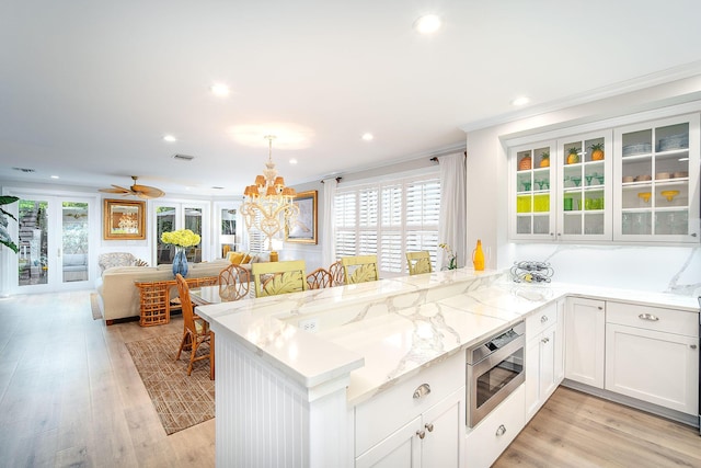 kitchen with pendant lighting, white cabinetry, plenty of natural light, stainless steel microwave, and kitchen peninsula