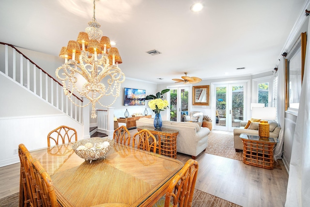 dining area featuring french doors, crown molding, ceiling fan with notable chandelier, and hardwood / wood-style floors