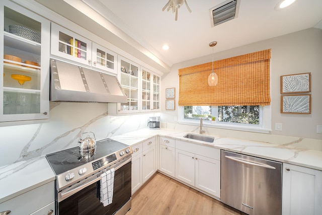 kitchen with appliances with stainless steel finishes, pendant lighting, sink, white cabinets, and light stone counters